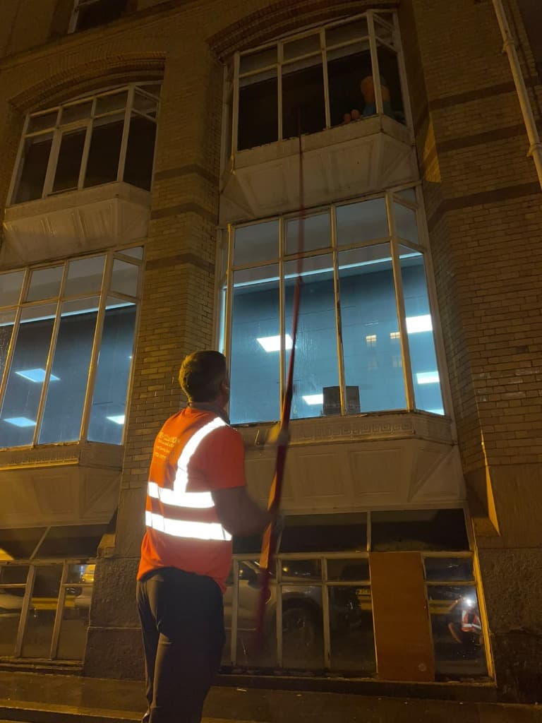 Operative using a water fed pole to clean commercial windows at night