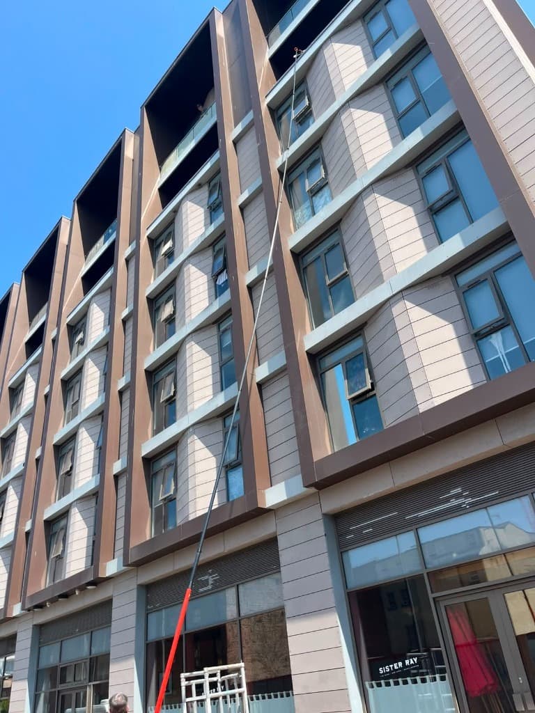 Water fed pole reaching windows several storeys up a panelled apartment building