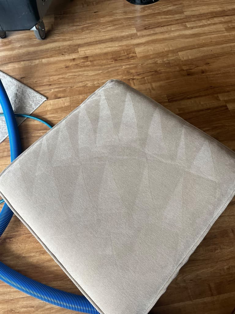 Sofa cushion being cleaned with an upholstery extraction tool